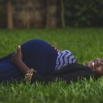 pregnant woman lying on green grass fields