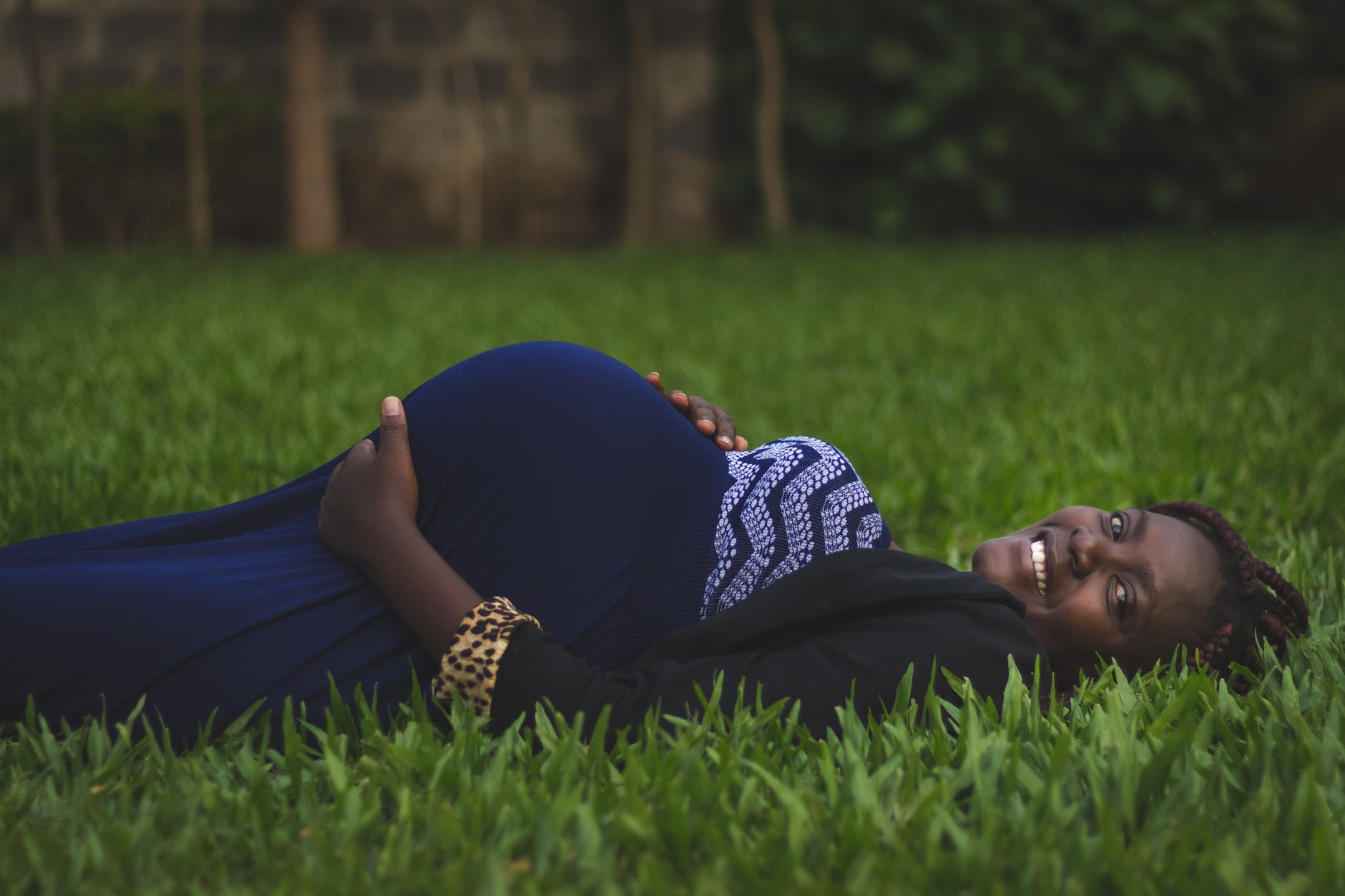 pregnant woman lying on green grass fields